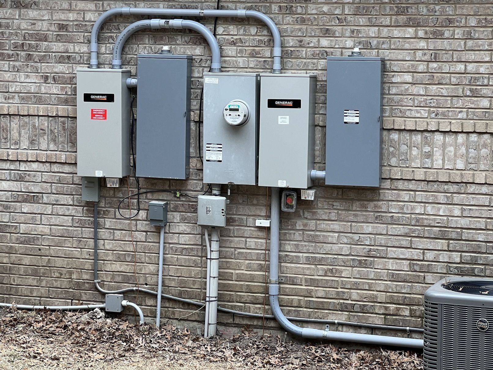 A Generac automatic transfer switch and electric meter mounted on the brick exterior of a home