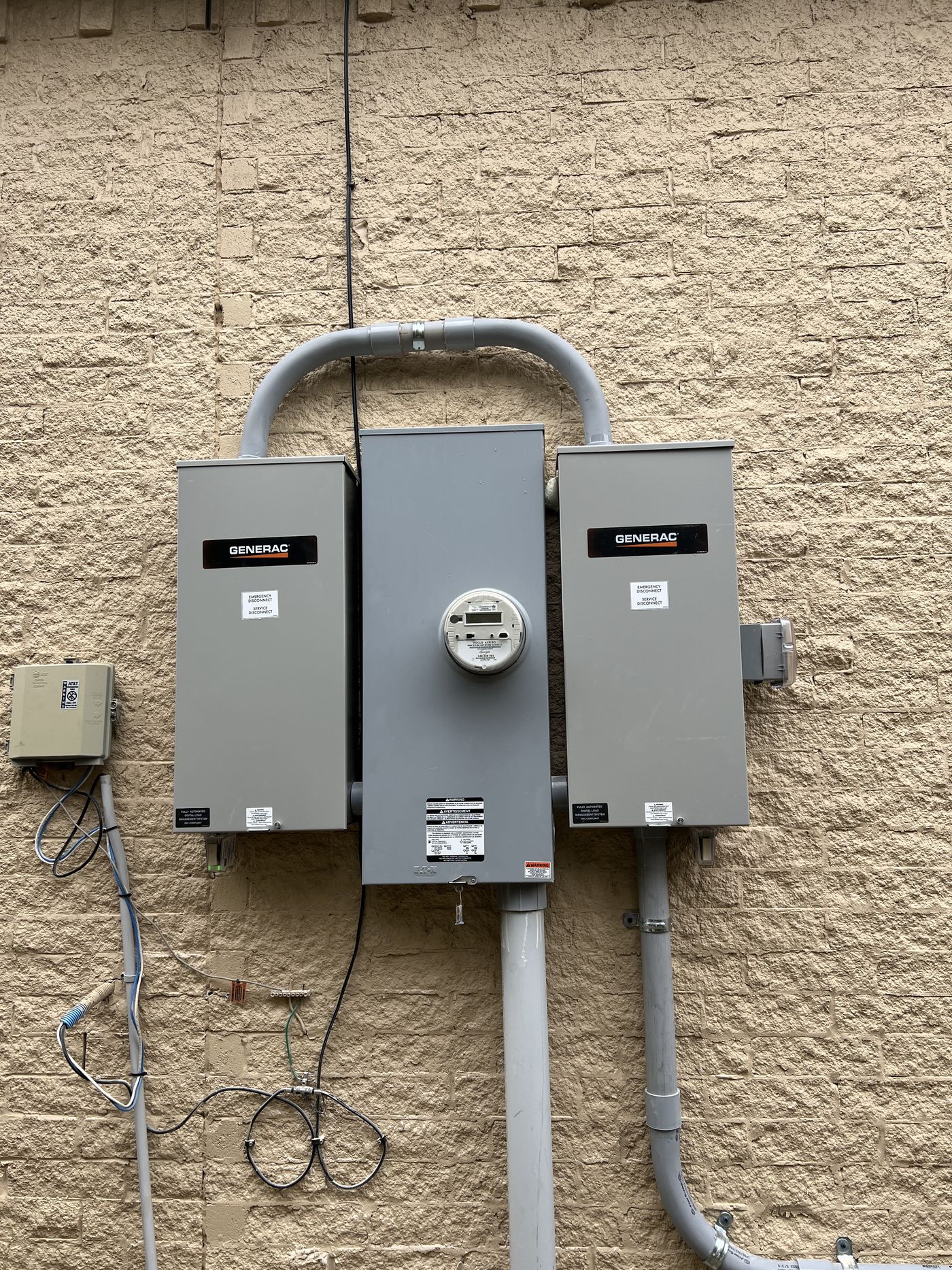 Two Generac automatic transfer switches mounted either side of the electric meter on an exterior wall